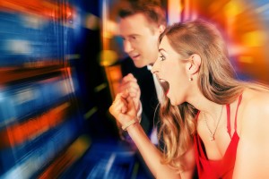 Gambling couple in Casino or amusement arcade on slot machine wi